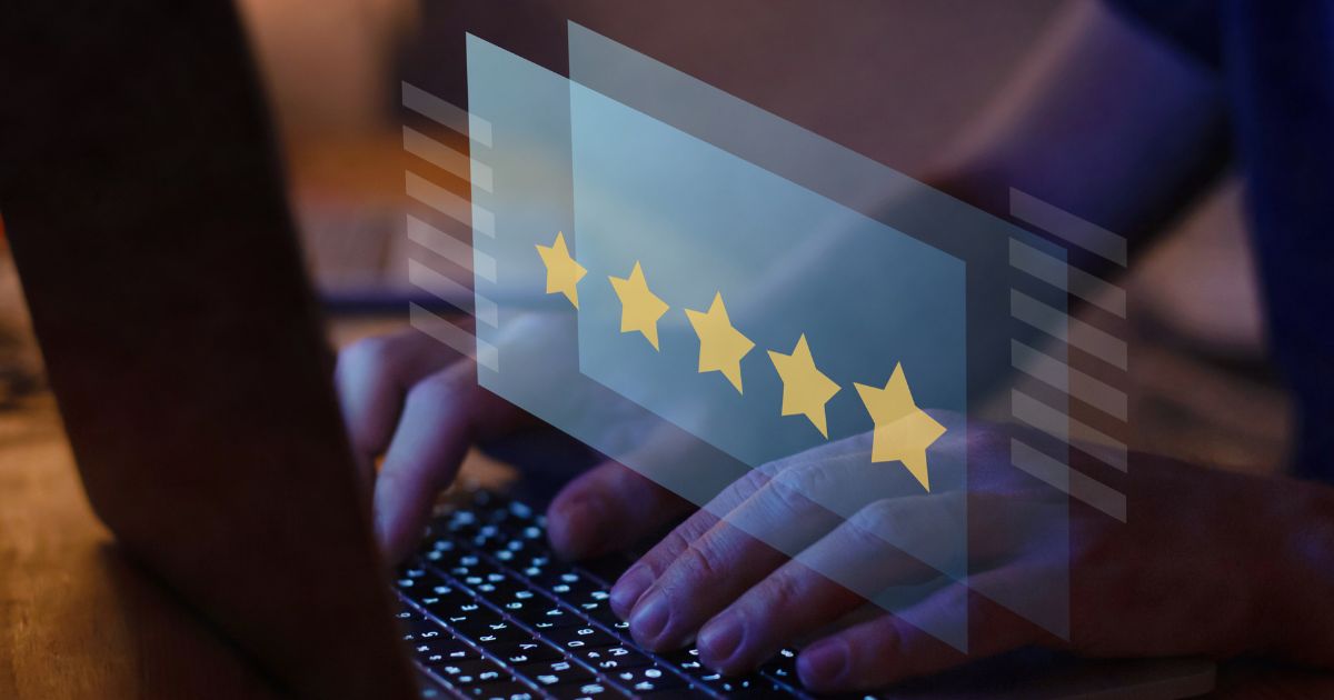 Reflection of laptop screen with five stars displayed over a person typing on the keyboard