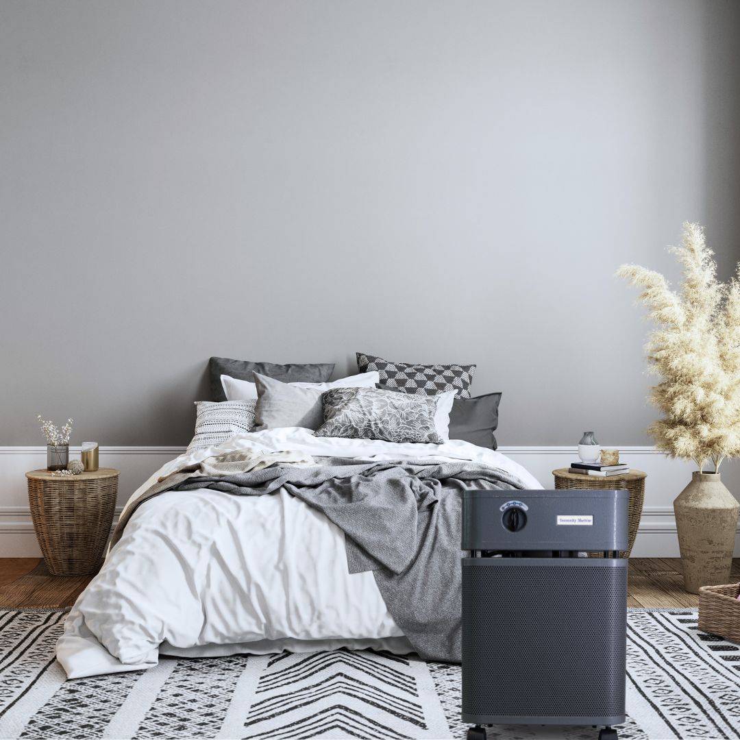 Air purifier on a rug in a bedroom with a bed and decorative items.