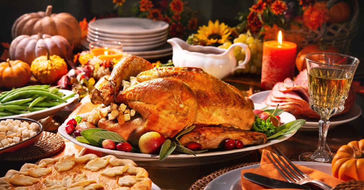 Thanksgiving dinner table with roasted turkey, pie, and pumpkins.