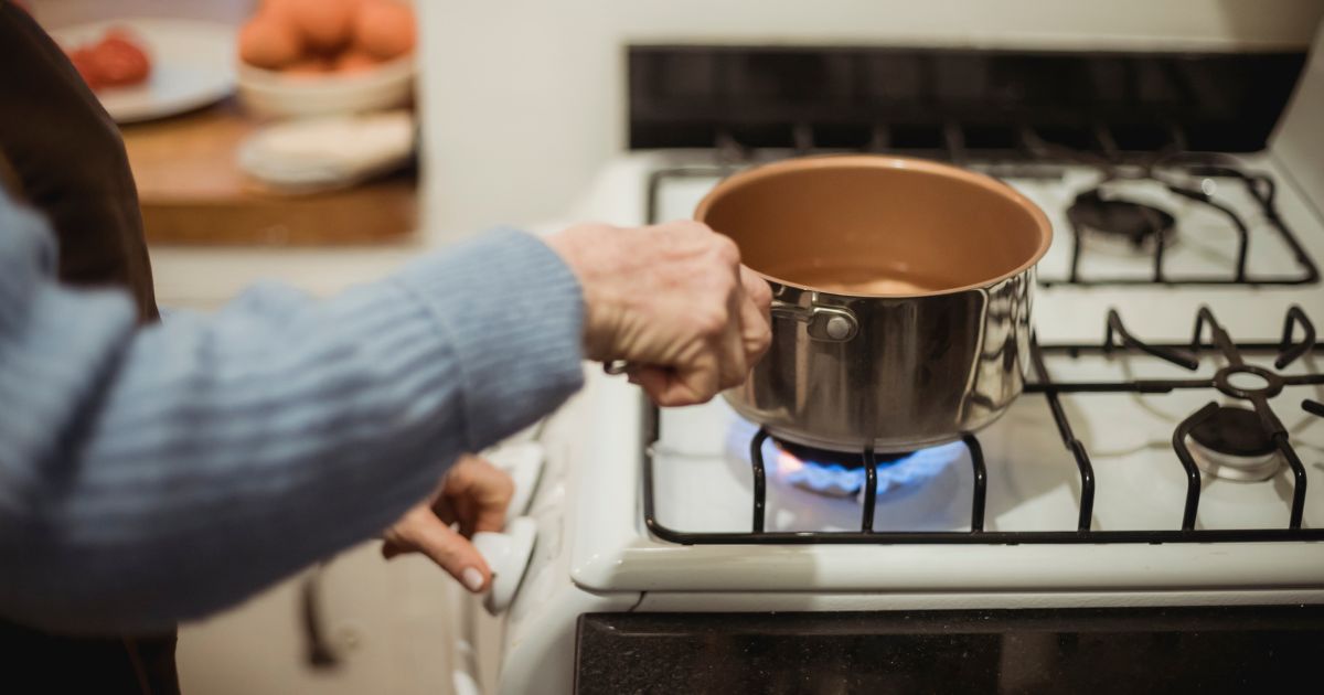 Person places copper pan on a gas stove