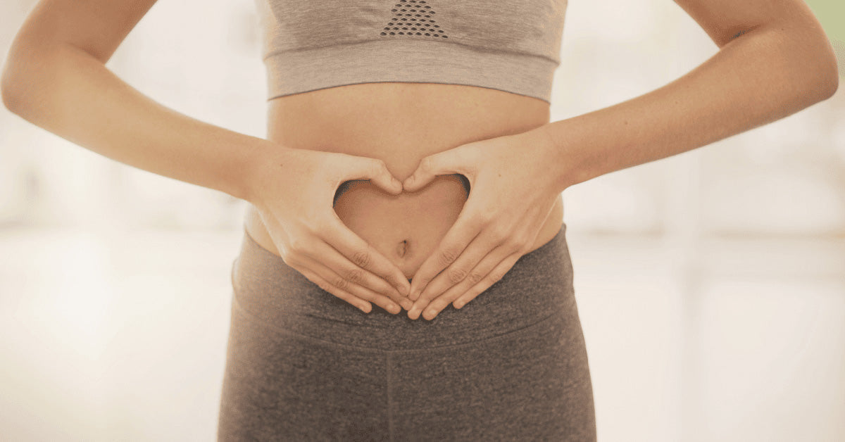 A woman holding her hands over her stomach in the shape of a heart 